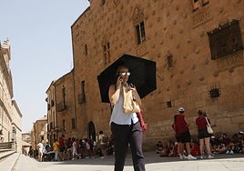 Una mujer se protege del sol con un paraguas.