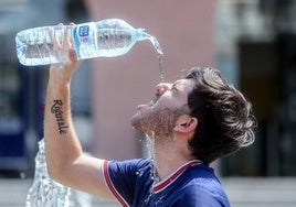 Un joven se tira una botella de agua por encima para combatir el calor.