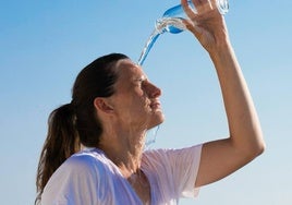 Una mujer se refresca con una botella de agua.