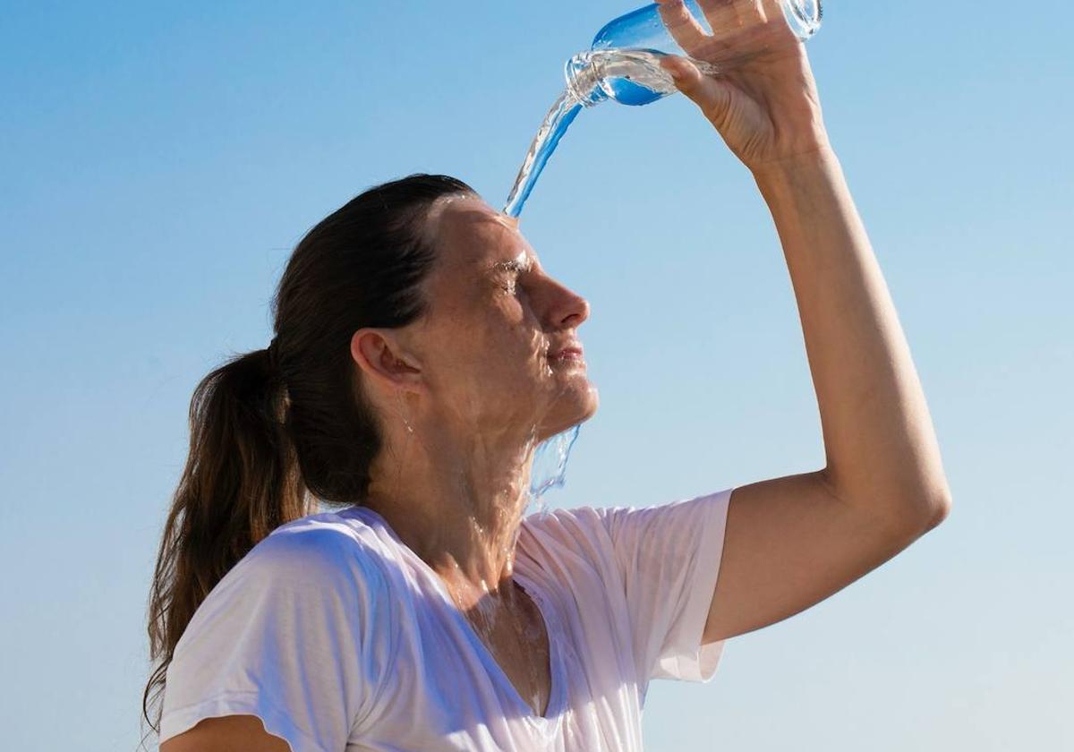 Una mujer se refresca con una botella de agua.