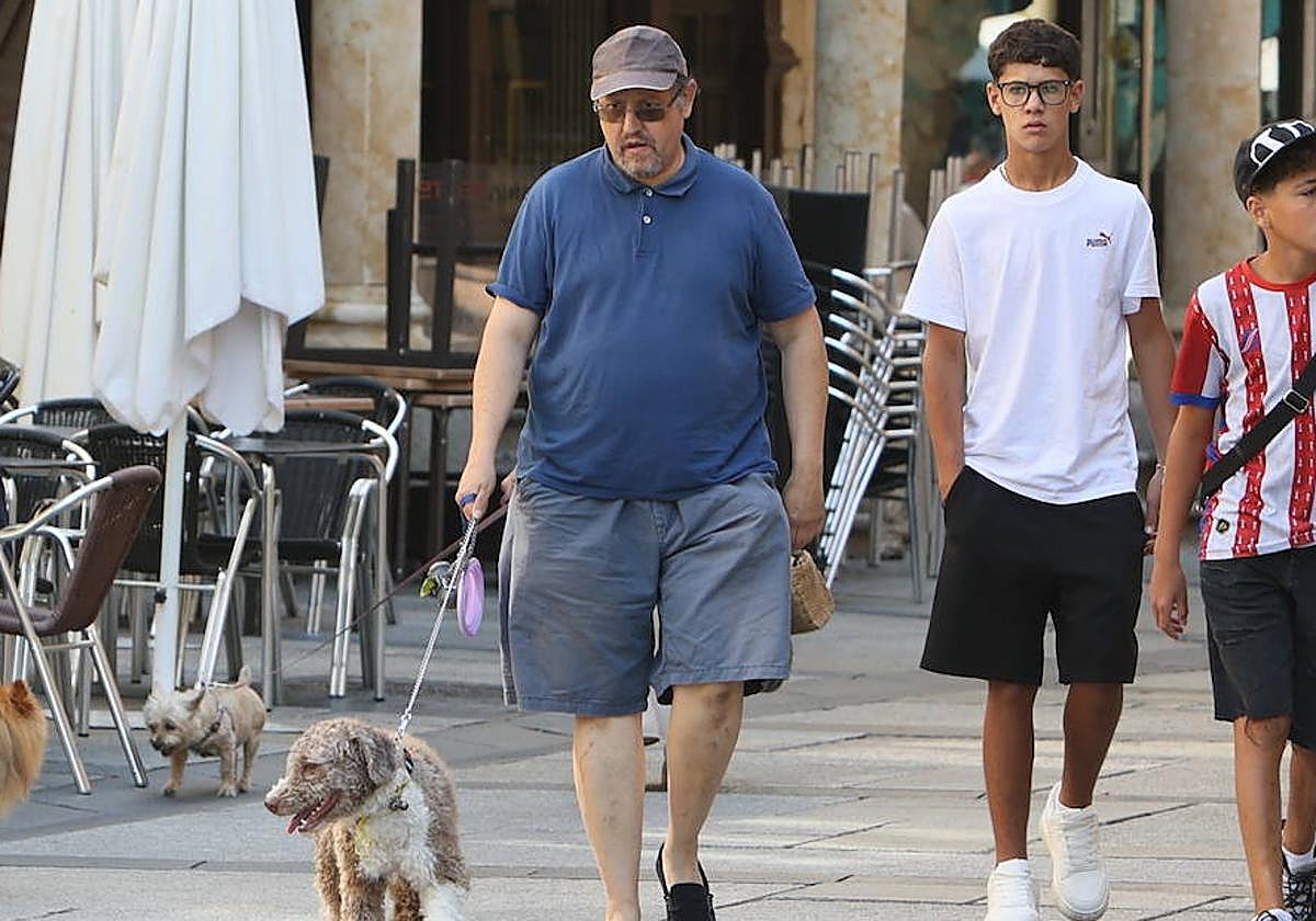 Un hombre pasea a su perro con correa y bolsas para recoger sus excrementos.