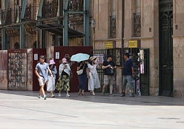 Varias personas se protegen del calor en Salamanca con gorras y paraguas.