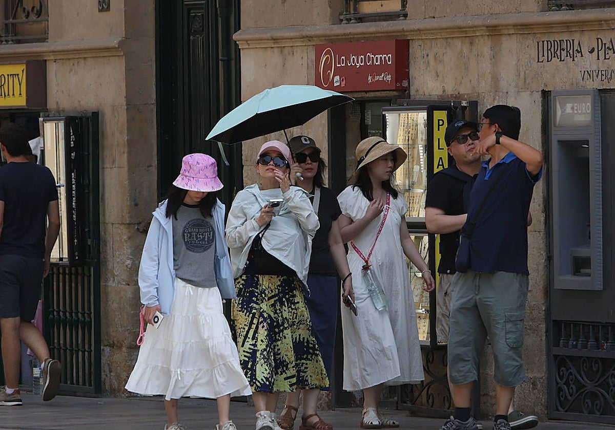 Varios turistas se protegen del calor en el centro de Salamanca.