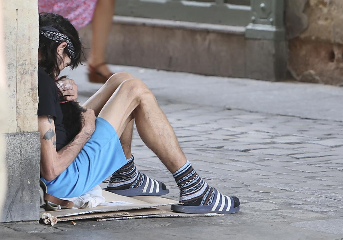 Un hombre, con su mascota, pidiendo limosna en la calle Prior.