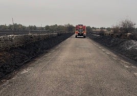 Un camión de bomberos, por una carretera que transcurre entre la zona quemada del incendio de Cipérez.
