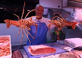 Un pescadero del Mercado sostiene dos langostas.