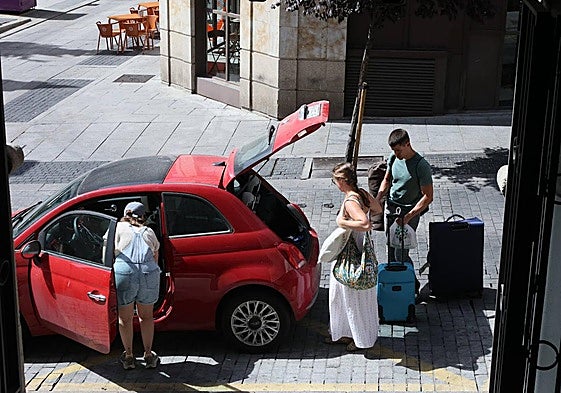 Una pareja prepara el equipaje en el coche antes de un viaje.