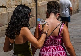 Dos chicas se refrescan con una botella de agua.