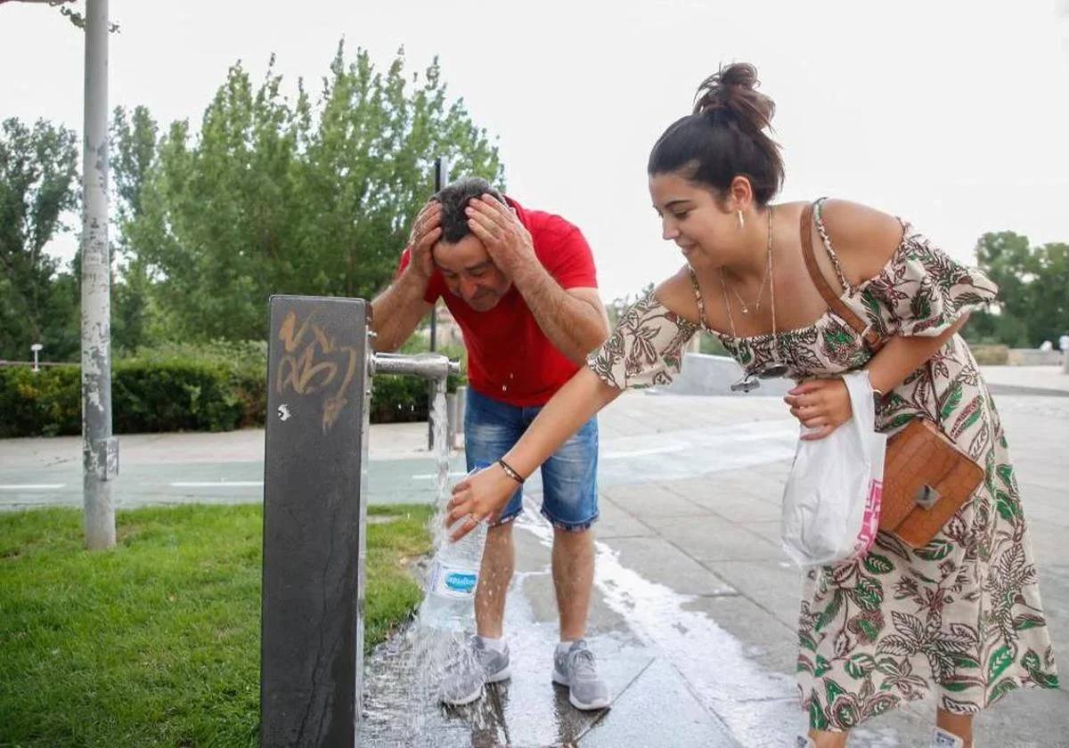 Personas refrescándose en una fuente ante las altas temperaturas.