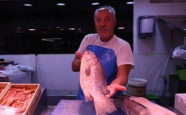 Un pescadero del Mercado muestra una merluza.