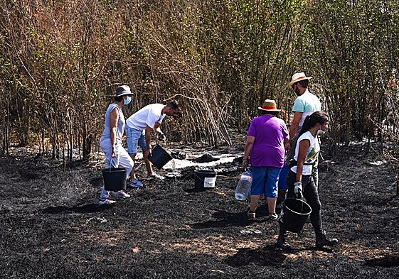 Vecinos, refrescando una zona afectada por un incendio este verano.