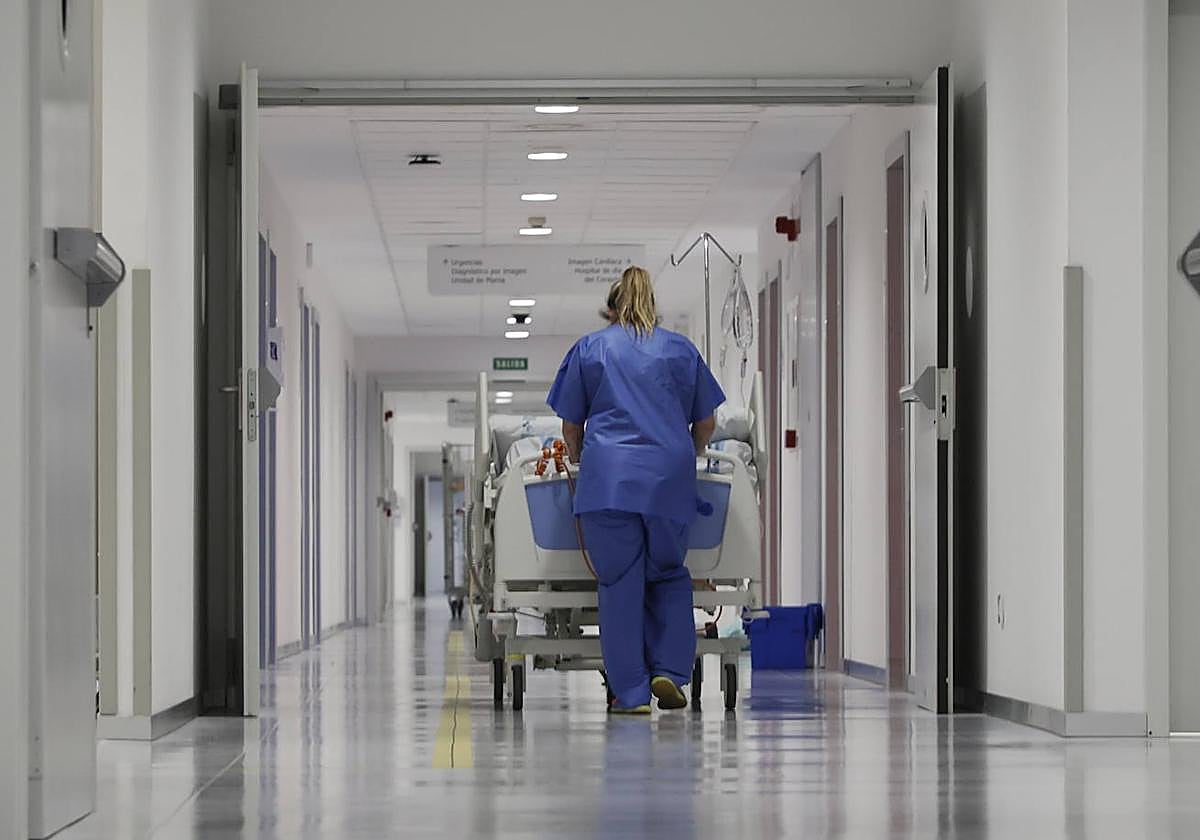 Una celadora traslada a un paciente por un pasillo del Hospital.