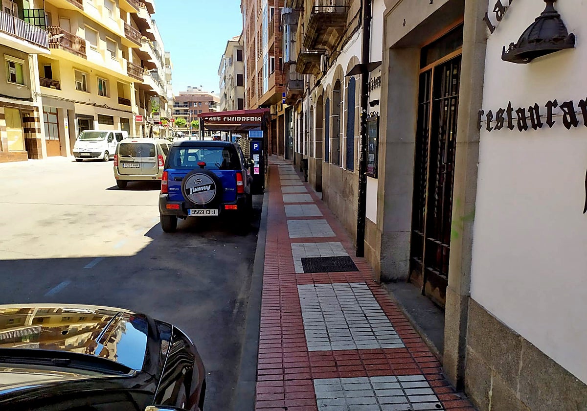 Coches aparcados en la Zona Azul en la calle Colón en Béjar con un expendedor al fondo.