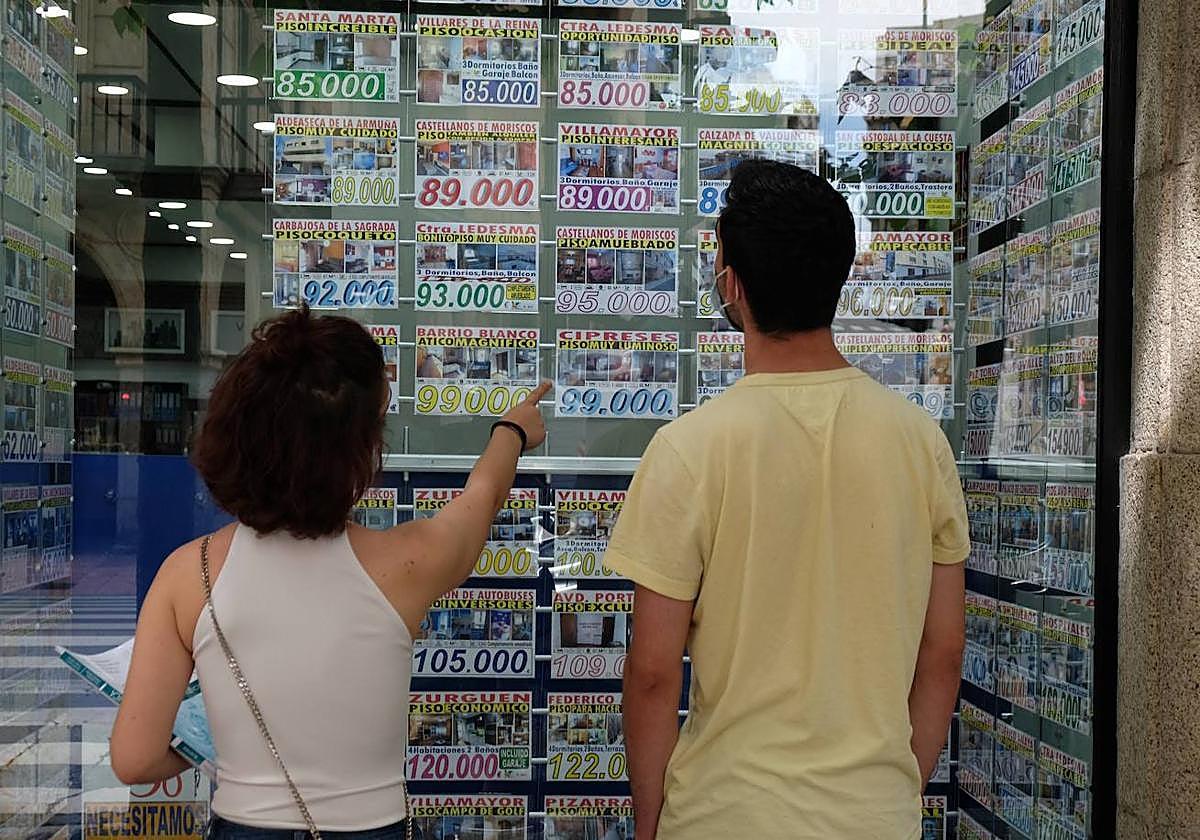 Dos personas miran el escaparate de una agencia inmobiliaria.