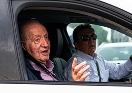El rey Juan Carlos saluda a su salida en un coche.