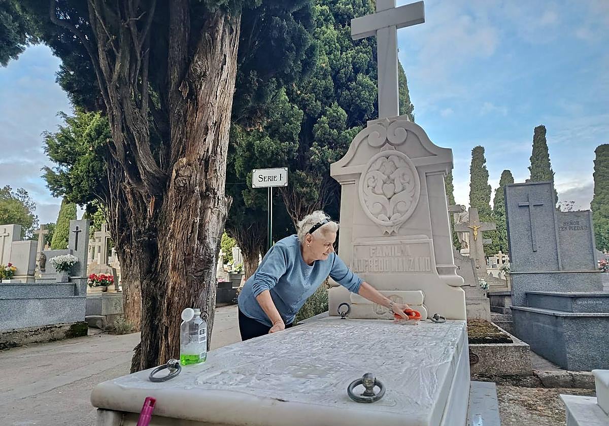 Una persona limpia una lapida del cementerio San Carlos de Borromeo con motivo del Día de Todos los Santos.