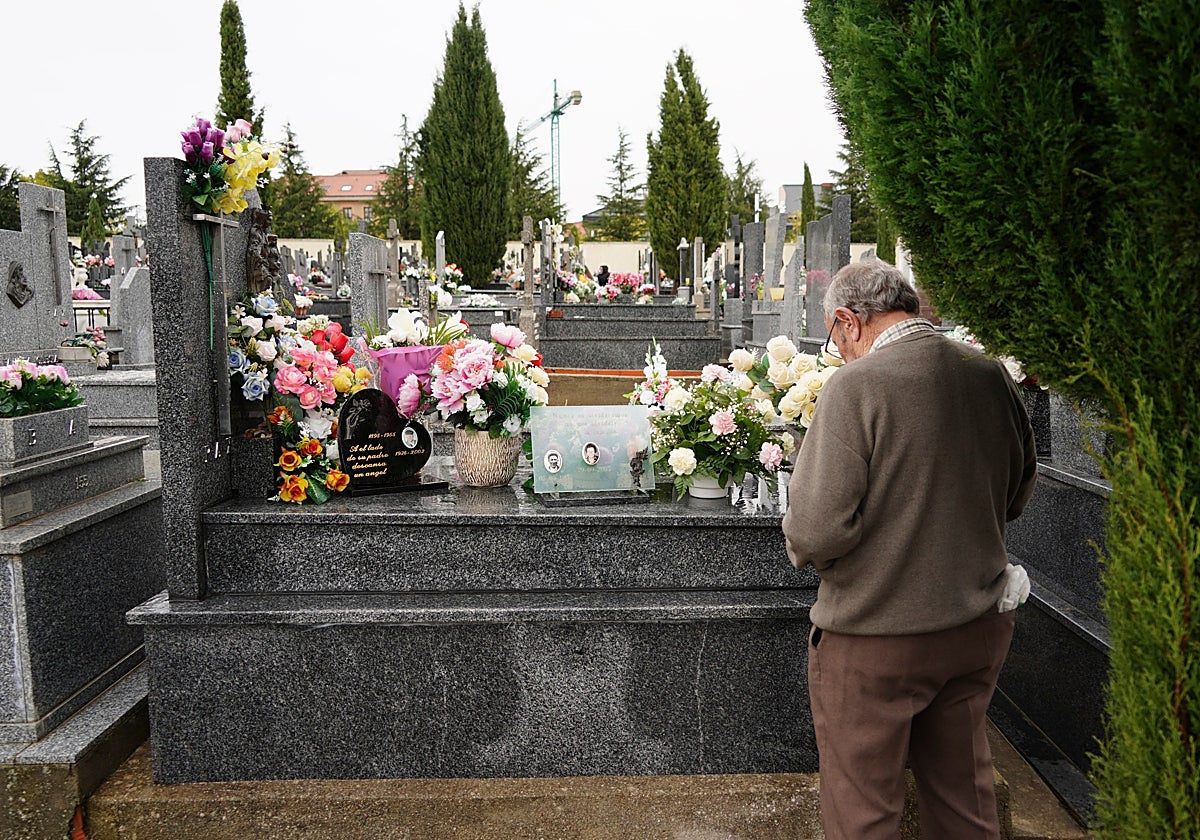 Un familiar reza ante la tumba de sus difuntos.