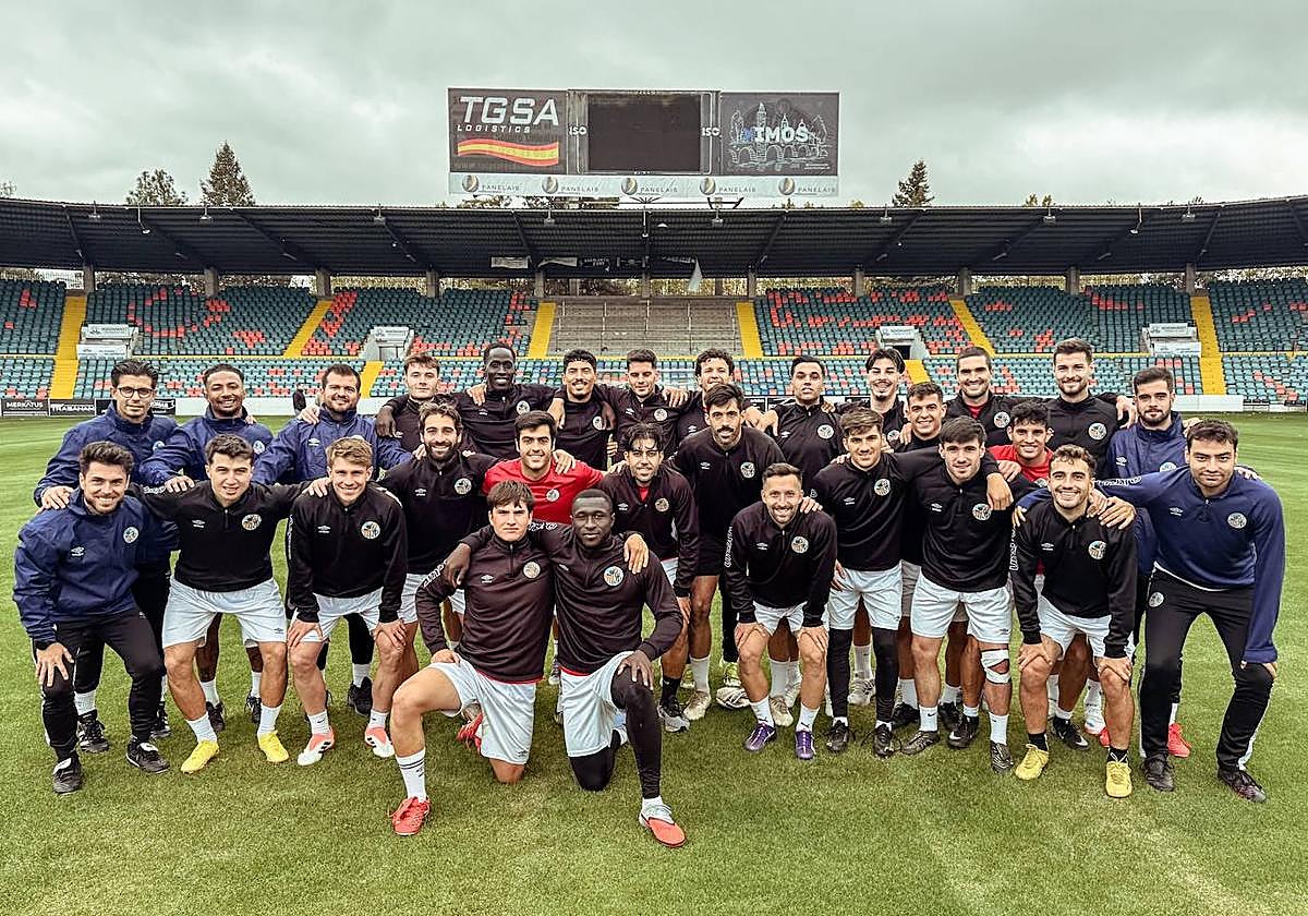 Jugadores y técnicos del Salamanca UDS, sonrientes sobre el césped del Helmántico.