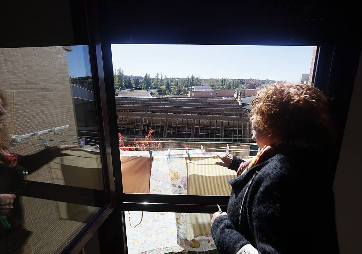Una vecina frente a su ventana desde la que se ve la antigua fábrica de lana abandonada.