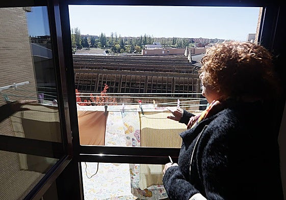 Una vecina frente a su ventana desde la que se ve la antigua fábrica de lana abandonada.