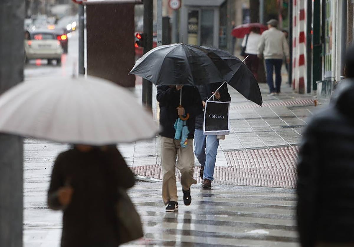 Un hombre se protege de la lluvia por las calles de Salamanca.