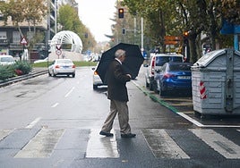 Un hombre se protege de la lluvia en un día lluvioso en Salamanca.