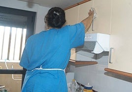 Una empleada de hogar limpia los muebles de la cocina.