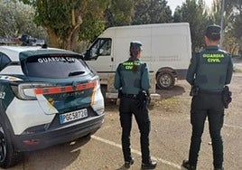 Dos agentes de la Guardia Civil, junto a la furgoneta intervenida.