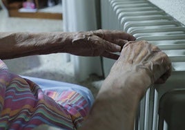 Una mujer se calienta acercándose a un radiador de su salón.