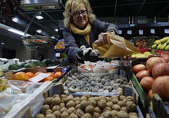 La frutera del puesto nº 46 sostiene unos higos secos.