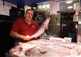 El pescadero del puesto nº 55, sosteniendo una corvina.