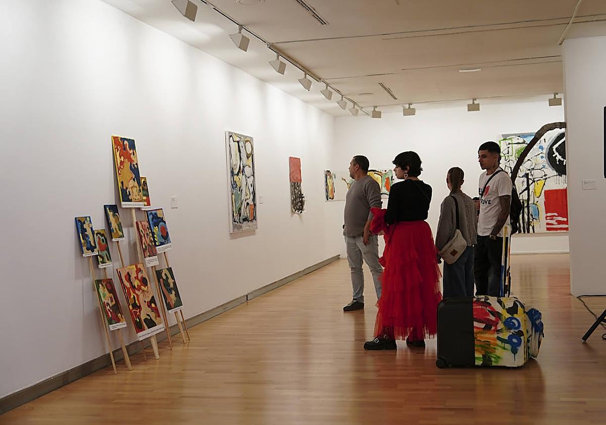 Imagen principal - Visitantes, observando la exposición.