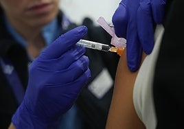 Una enfermera, poniéndole una vacuna a una persona.