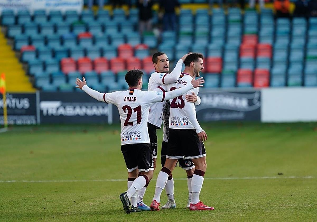 Casado y Aimar felicitan a Delgado, que este domingo anotó dos tantos.