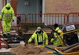 Operarios municipales, trabajando para limpiar el depósito de agua en una calle de Salamanca.