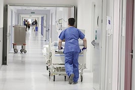 Un celador, trasladando en camilla a un paciente.