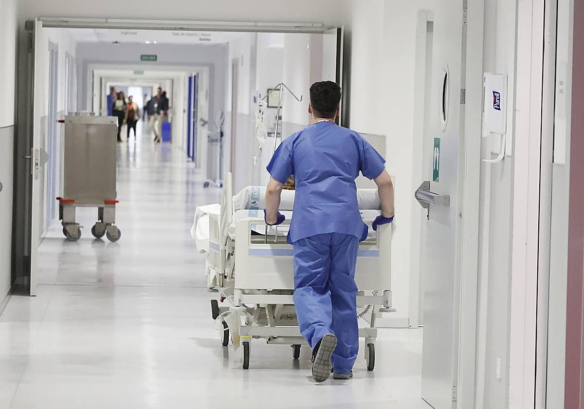 Un celador, trasladando en camilla a un paciente.