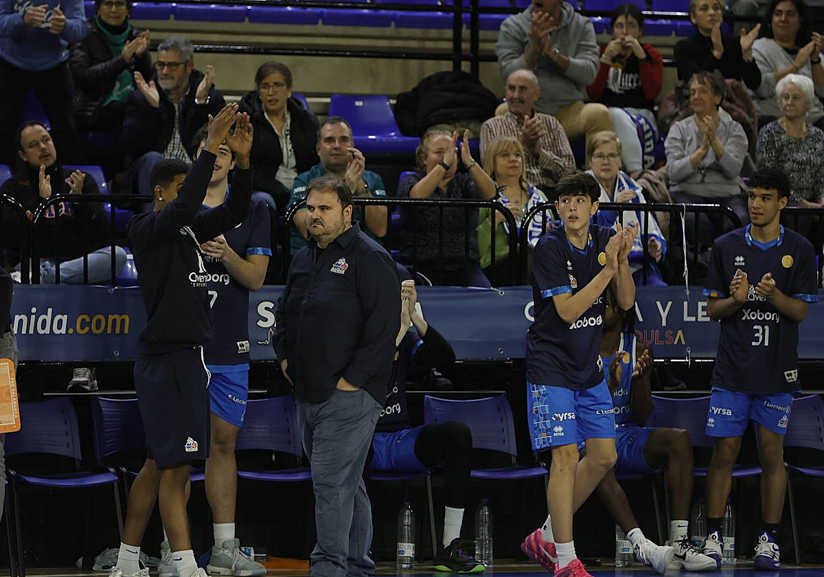 El banquillo del Perfumerías Avenida Xoborg celebra una canasta salmantina mientras Bellido camina serio.