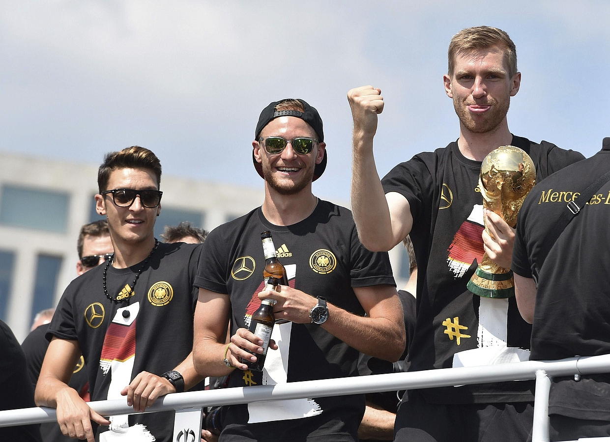 LA SELECCIÓN ALEMANA CELEBRA LA COPA DEL MUNDO CON MILES DE AFICIONADOS. Mesut Özil (i-d), Benedikt Hoewedes y Per Mertesacker celebran la Copa del Mundo de la FIFA con cientos de miles de aficionados a su llegada a la Puerta de Brandeburgo a bordo de un autobús sin techo, en Berlín.