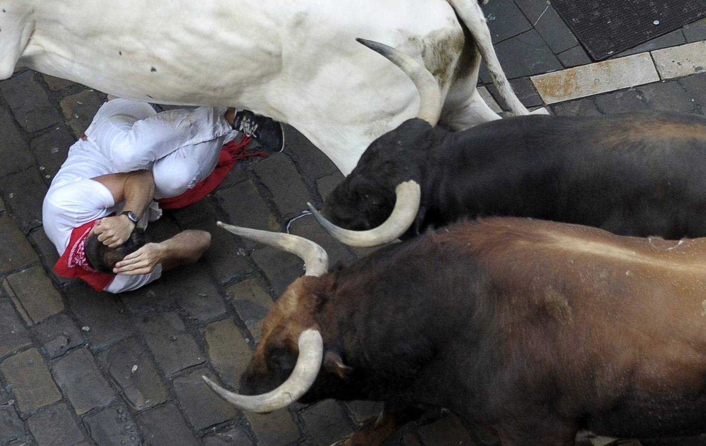 Uno de los mozos se protege del ataque de un toro en la Curva de Mercaderes.