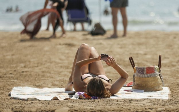 Una mujer consulta el móvil desde la playa. :: MANUEL BRUQUE / efe