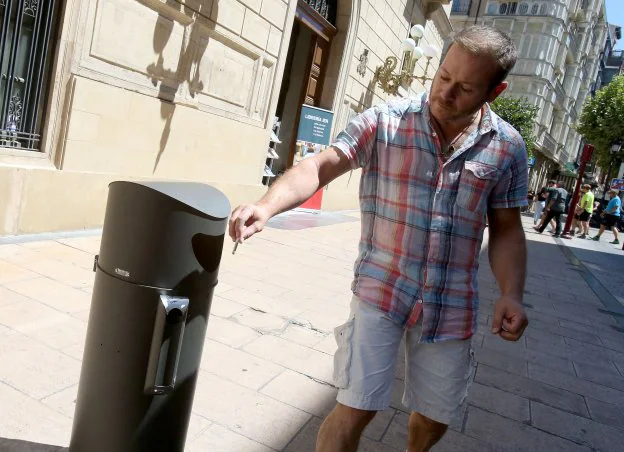 Un hombre deposita la colilla en la 'papelera-cenicero' instalada ayer, a modo de prueba, en Portales, junto al IER. :: juan maRín