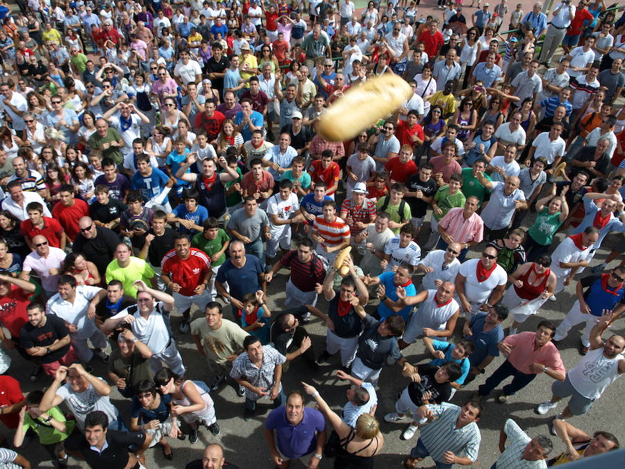 Los cofrades de la Cofradía de la Transfiguración del Señor arrojan, desde la balconada de la ermita, el pan y el queso, según la tradición del llamado "panyqueso de Quel"