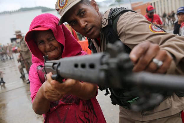 Un miembro de la milicia enseña a una mujer a usar un rifle. :: reuters