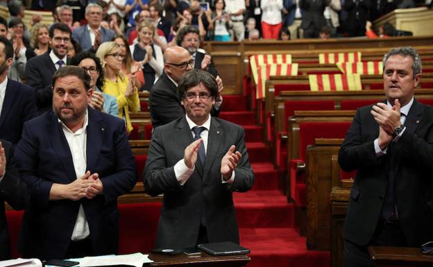 Junqueras (i) y Puigdemont (c) aplauden tras la votación. 