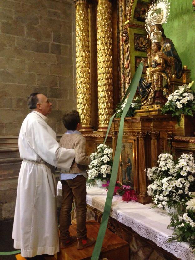 El hermano mayor, Mariano Moracia, acerca un niño a la virgen. Arriba, el broche conmemorativo. :: l.R.