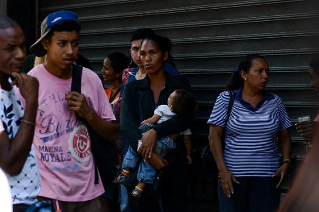 Una mujer con su bebé en una de las habituales colas para conseguir comida a las puertas de un supermercado en Caracas. :: F. P. / efe
