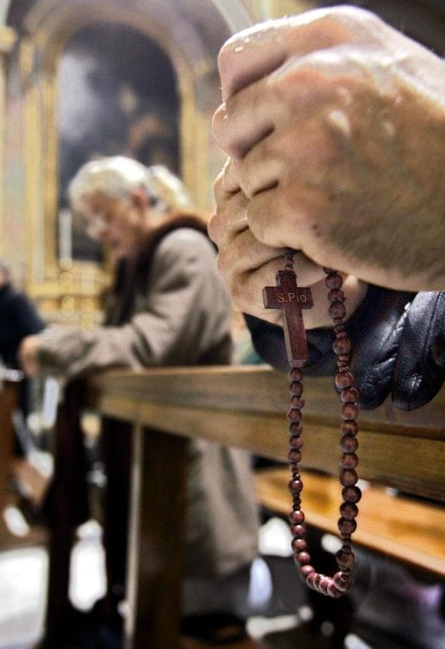 Varias personas rezan en el interior de una iglesia. 