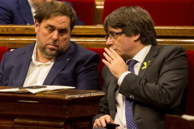 Oriol Junqueras y Carles Puigemont conversan durante una sesión del Parlament. :: Quique García/ efe