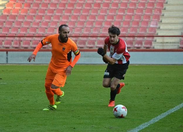 Navarro saca el balón del área visitante presionado por el delantero blanquirrojo Rubén Peña. :: sergio martínez
